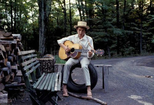 Una foto di Bob Dylan seduto tra il verde dell'area di Big Pink